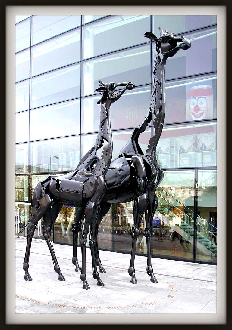 Helen Denerley (b. 1956 in Midlothian, Scotland. Now living in Strathdon, Aberdeenshire, Scotland). Dreamings Spires. 2005. Discarded steel parts of motorbikes and cars. The largest of the two giraffes is 22 ft high. On the pavement in front of The Omni Centre, Leith Walk, Edinburgh, Scotland. http://www.edinphoto.org.uk/0_buildings_g/0_buildings_-_omni_centre_and_giraffes_001884.htm#picture